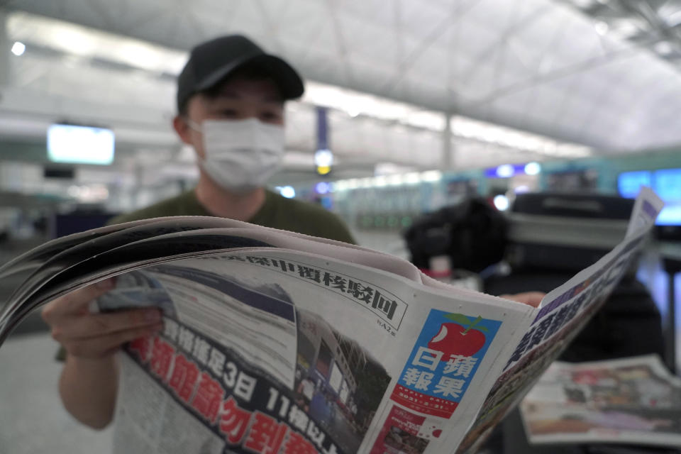 Mike Hui reads the Apple Daily newspaper before his departure to England, at an airport in Hong Kong on May 21, 2021. Until early April, Hui was a photojournalist for the Apple Daily, a pro-democracy newspaper that shut down following the arrest of five top editors and executives and the freezing of its assets under a national security law that China's ruling Communist Party imposed on Hong Kong as part of the crackdown. (AP Photo/Kin Cheung)
