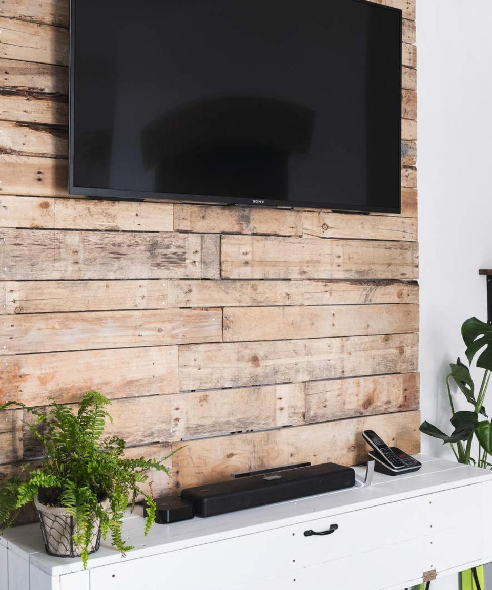 A flat-screen TV affixed to a wooden bedroom wall