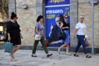 People walk past a Russian Liberal Democratic Party poster with an image of former party leader Vladimir Zhirinovsky prior to local elections in Donetsk, the capital of Russian-controlled Donetsk region, eastern Ukraine, on Thursday, Sept. 7, 2023. (AP Photo)