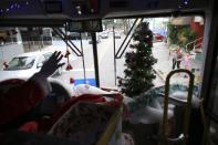 Bus driver Edilson, 45, also known as "Fumassa", greets a mother with her daughter as he wears a Santa Claus outfit inside an urban bus decorated with Christmas motives in Santo Andre, outskirts of Sao Paulo December 10, 2013. Fumassa dresses as Santa Claus every year while driving his bus. Picture taken December 10. REUTERS/Nacho Doce (BRAZIL - Tags: SOCIETY TRANSPORT)