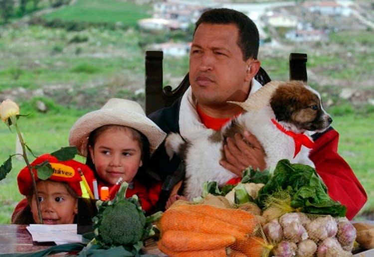 Acompañado por dos niñitas, Hugo Chávez sostiene un cachorro mucuchíes durante su programa televisivo "Aló Presidente" el 18 de mayo del 2003. Chávez evitó la extinción de los mucuchíes porque un animal de esa raza acompañó a Simón Bolívar en sus campañas y ha hecho que el animal sea parte de la identidad nacional venezolana. (AP Photo/Oficina de Prensa de la Presidencia de Venezuela, File)