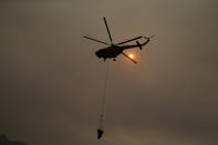 A firefighting helicopter takes water from the Aegean Sea near the Kemerkoy Power Plant, a coal-fueled power plant, in Milas, Mugla in southwest Turkey, Thursday, Aug. 5, 2021. A wildfire that reached the compound of a coal-fueled power plant in southwest Turkey and forced evacuations by boats and cars, was contained on Thursday after raging for some 11 hours, officials and media reports said. (AP Photo/Emre Tazegul)