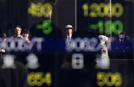 Pedestrians are reflected in an electronic board showing stock prices outside a brokerage in Tokyo December 12, 2013. REUTERS/Yuya Shino