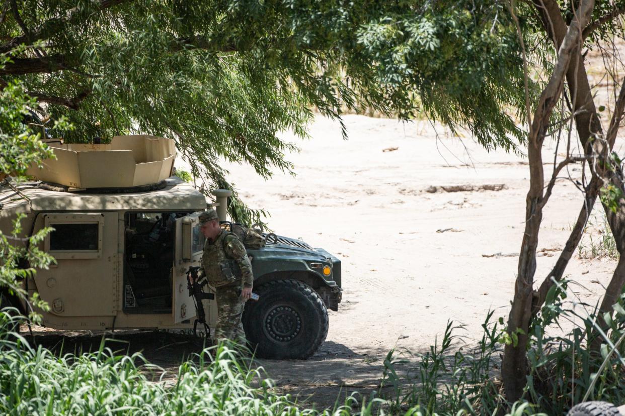 A National Guard member carries a rifle to a military-style vehicle near Shelby Park on Friday