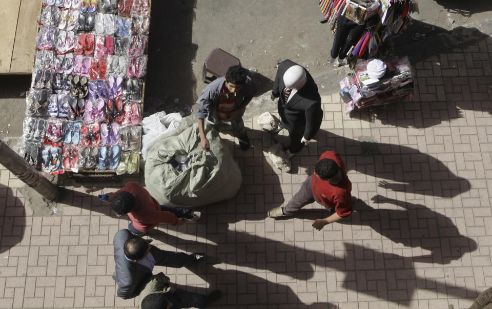 In this Tuesday, March 4, 2014 photo, a T-shirt vendor, a colleague of Rashad Abdel Hameed, sells T-shirts on a sidewalk in downtown Cairo, Egypt. Hameed, who is selling them on Cairo's sidewalks since he was 15, is starting a company to sell Egyptian-made T-shirts. Hameed, known as Mido, said many of the younger sellers now look up to him and come see him for advice. (AP Photo/Amr Nabil)