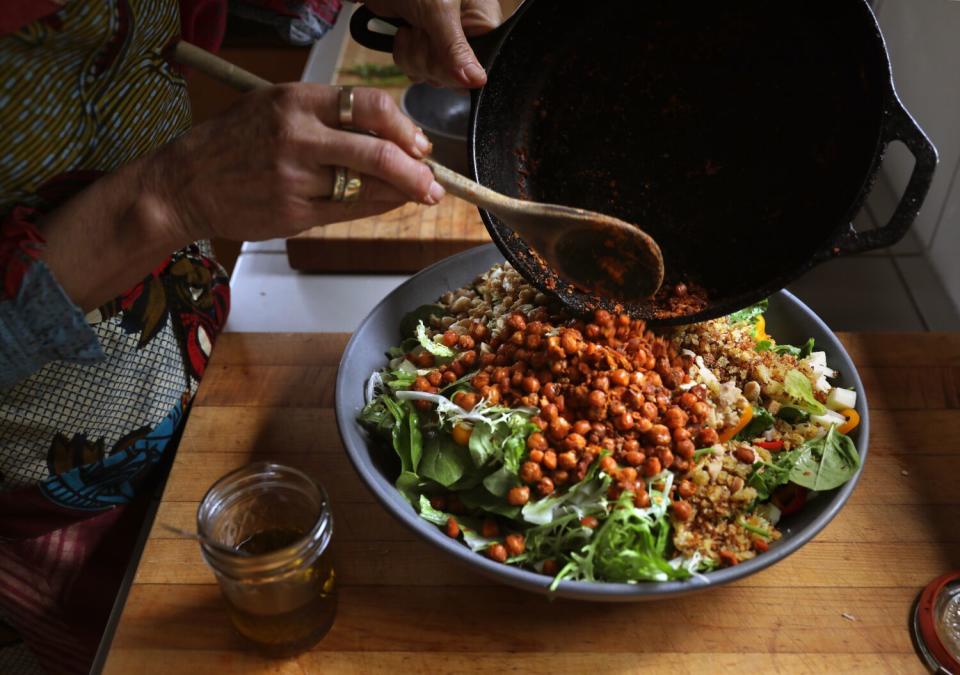 Hands preparing a large bowl of chopped salad.