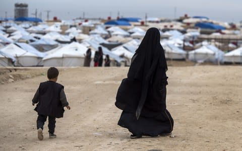 A displaced Syrian woman and a child walk toward tents at the Internally Displaced Persons (IDP) camp of al-Hol in al-Hasakeh governorate in northeastern Syria - Credit: AFP