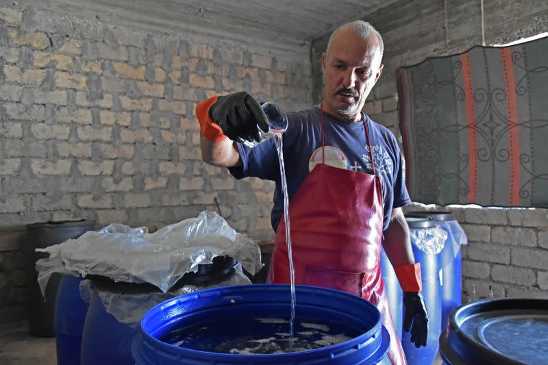 Saad Hussein, an Iraqi Yazidi, pours Arak into a fermentation tank to produce on the outskirts of Mosul