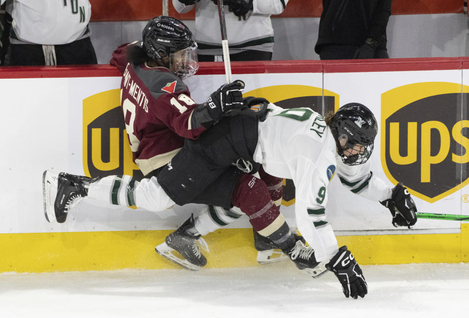 Montreal's Mikyla Grant-Mentis (18) and Boston's Sophie Shirley (9) battle on the boards during second-period PWHL playoff hockey game action in Laval, Quebec, Saturday, May 11, 2024. (Christinne Muschi/The Canadian Press via AP)