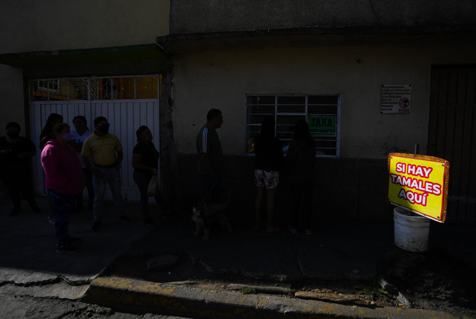 Clientes esperan en fila para comprar tamales en el exterior de una vivienda donde se elaboran a mano, en el vecindario de San Felipe de Jesús, en la Ciudad de México, el 25 de enero de 2023. Los tamales se consumen en numerosos países de Latinoamérica y el Caribe con denominaciones como “humita”, “pamonhas” “hallaca” y “guanime". (AP Foto/Fernando Llano)