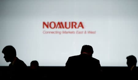 Investors stand in front of a screen showing the logo of Nomura Holdings in Tokyo, Japan, December 1, 2015. REUTERS/Toru Hanai/File Photo