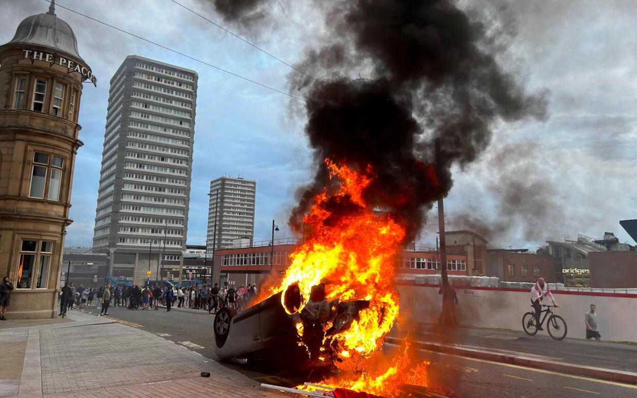 A car is toppled over and set alight during scenes of disorder in Sunderland