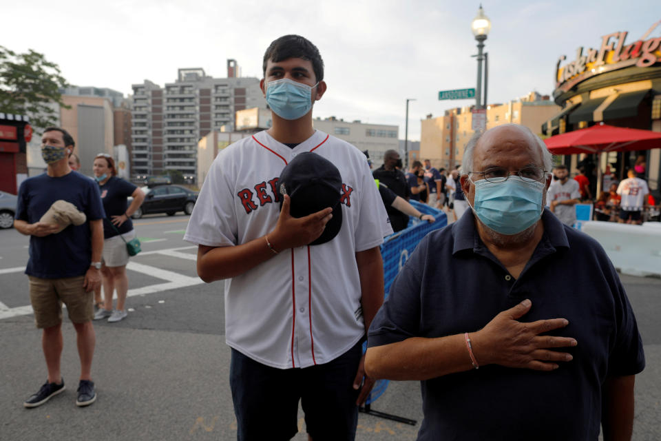 Fans outside the ballpark stand as the U.S. National Anthem is performed inside Fenway Park before the shortened season opening MLB baseball game between the Baltimore Orioles and the Boston Red Sox, played before an empty ballpark because of the coronavirus disease (COVID-19) outbreak, in Boston, Massachusetts, U.S., July 24, 2020.   REUTERS/Brian Snyder     TPX IMAGES OF THE DAY