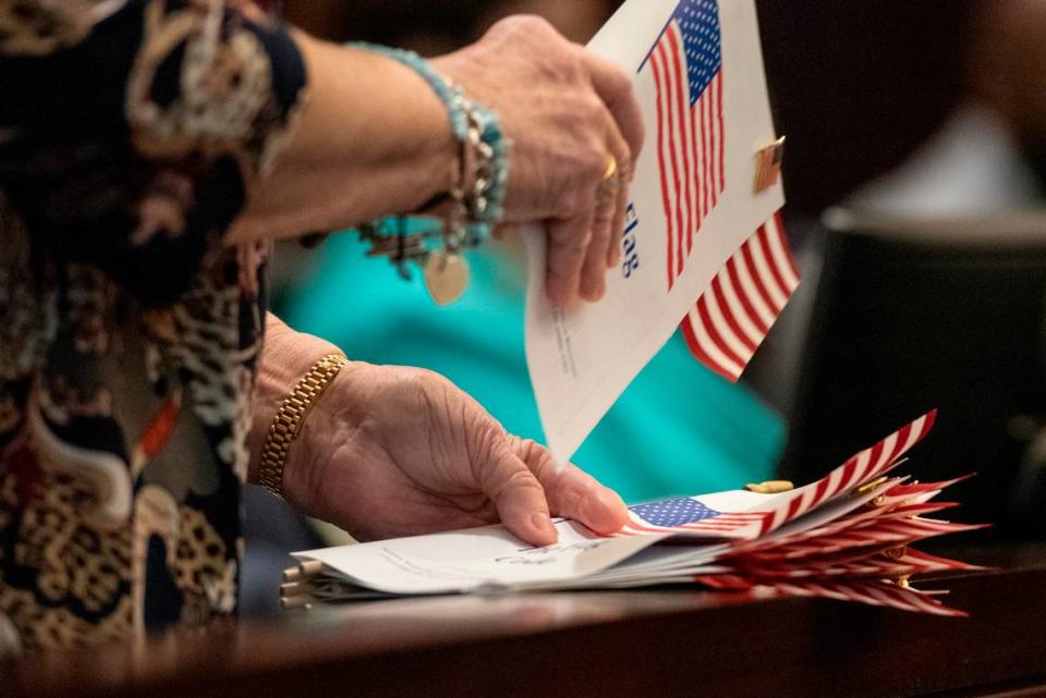Members of daughters of the American Revolution hand out American flags and pins to newly naturalized American citizens during a naturalization ceremony at Dan M. Russell Courthouse in Gulfport on Thursday, Oct. 19, 2023.