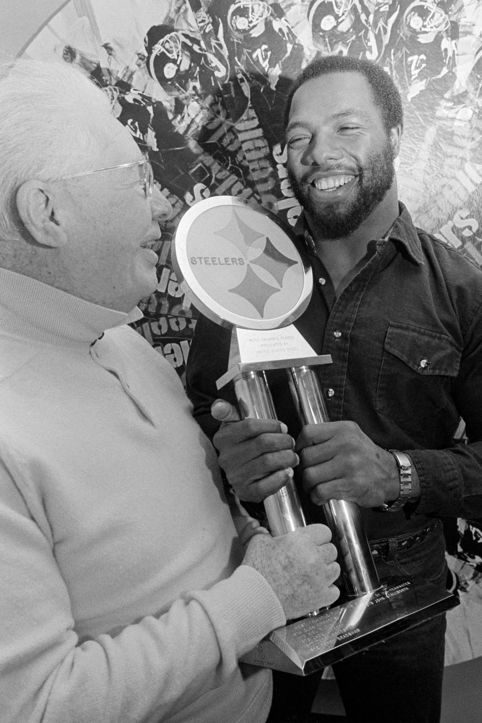 FILE - Pittsburgh Steelers strong safety Donnie Shell, right, accepts the trophy for being named the Steelers' Most Valuable Player, from team vice president and chairman of the board Art Rooney, in Pittsburgh, in this Dec. 16, 1980, file photo. “Chuck Noll had that saying, ‘Whatever it takes’ and Donnie was kind of the definition of that,” Steelers president Art Rooney II said. The hard-hitting cornerback won four Super Bowls during his 14 years in the NFL and next month will become the fifth — and most unlikely — member of the “Steel Curtain” defense to be enshrined in Canton.(AP Photo/Gene Puskar, File)