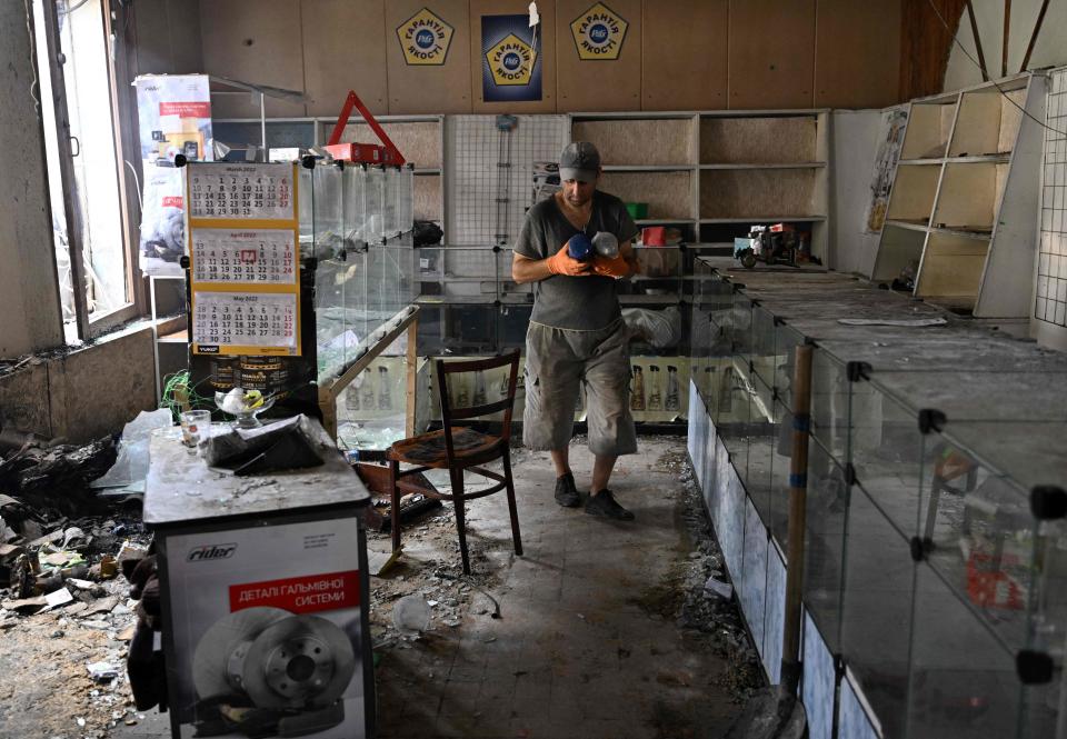 A shop worker carries away some goods from a destroyed store in a local market in Sloviansk (AFP via Getty Images)