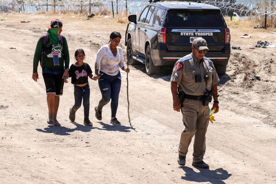 PHOTO: A Texas Department of Safety officer walks with migrants near the Rio Grande in Eagle Pass, Texas, Sept. 21, 2023. (Adam Davis/EPA via Shutterstock)