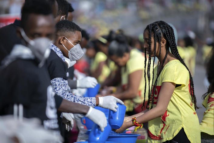 Volunteers, left, provide soap and water for participants to wash their hands against the new coronavirus at a women's 5km fun run in the capital Addis Ababa, Ethiopia Sunday, March 15, 2020. Ethiopia reported on Thursday its first case of the new coronavirus which causes COVID-19. For most people, the new coronavirus causes only mild or moderate symptoms, such as fever and cough but for some, especially older adults and people with existing health problems, it can cause more severe illness, including pneumonia. (AP Photo/Mulugeta Ayene)