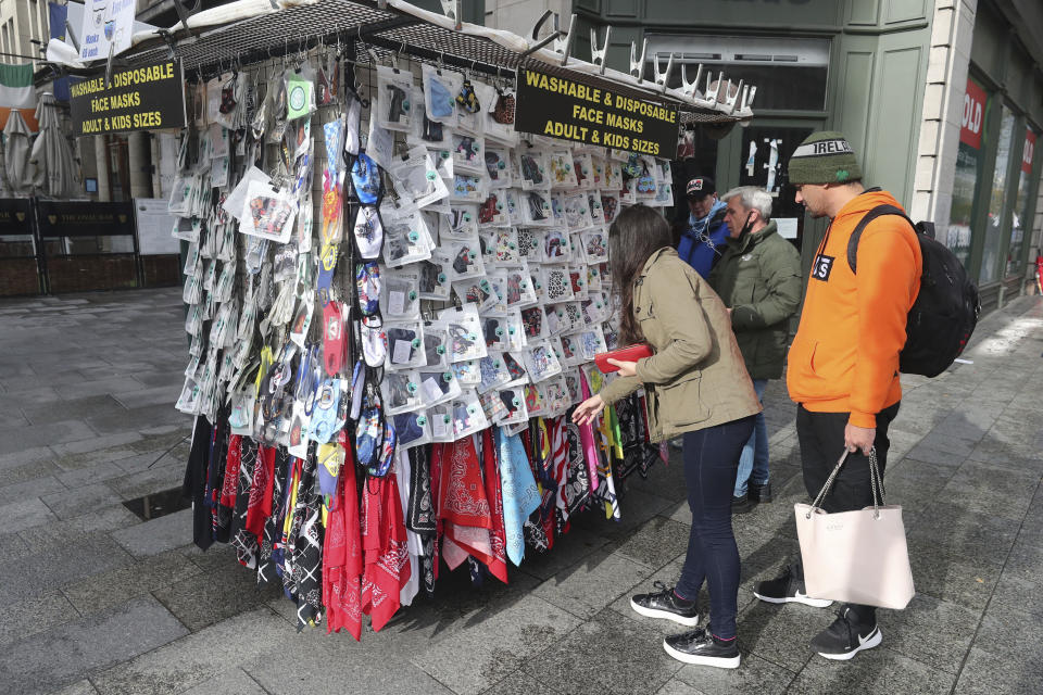 Shoppers buy face masks on O'Connell Street in Dublin city centre, Tuesday Oct. 20, 2020. Ireland's government is putting the country at its highest level of coronavirus restrictions for six weeks in a bid to combat a rise in infections. The measures take effect at midnight Wednesday and run until Dec. 1. (Niall Carson/PA via AP)