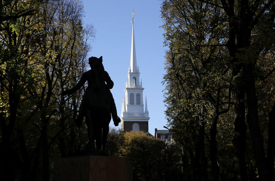 In this Wednesday, Nov. 7, 2018 photo Old North Church stands behind a statue of Paul Revere in the North End neighborhood of Boston. A bronze wreath and plaque that forms part of a memorial, which includes thousands of dog tags honoring soldiers killed in Iraq and Afghanistan, has been installed on the grounds of the church. The new plaque and wreath help explain the meaning of the dog tags and acknowledge Britain's contribution and sacrifice. (AP Photo/Steven Senne)