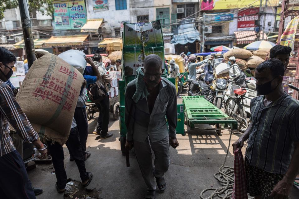 A worker pulls a loaded cart into an alley in Fatehpuri Market after the government eased a nationwide lockdown imposed as a preventive measure against the COVID-19 coronavirus in New Delhi on June 12, 2020. (Photo by XAVIER GALIANA / AFP) (Photo by XAVIER GALIANA/AFP via Getty Images)