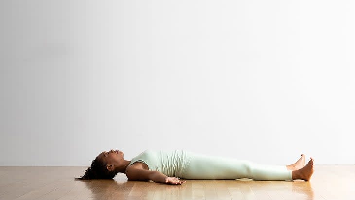 A person demonstrates Savasana (Corpse Pose) in yoga