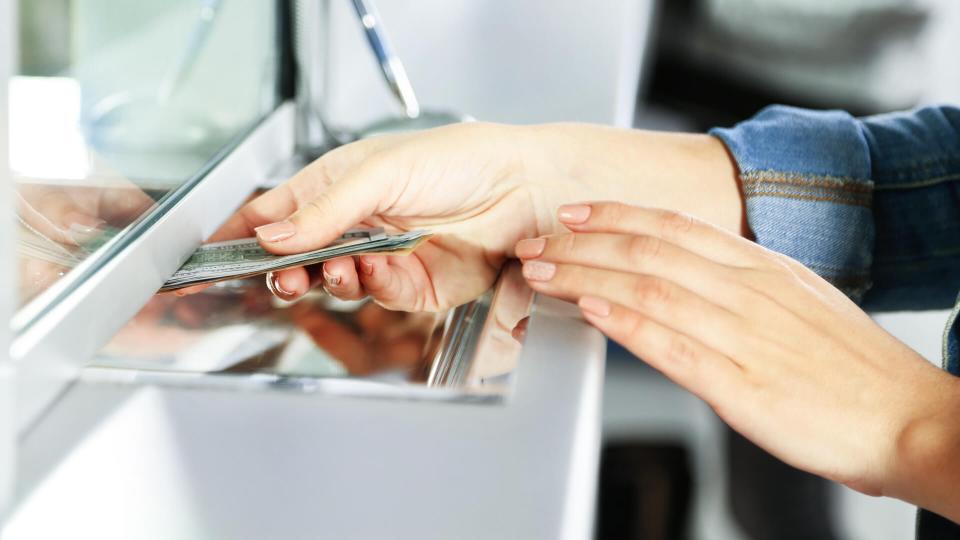 Female hand with money in cash department window.