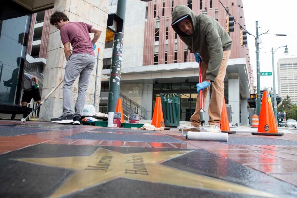 Stagehands Robert Kyle and Jonathan White roll a sealer onto the bricks and stone surrounding the Orpheum Theatre Group’s Sidewalk of Stars as Marvin Hamlisch’s star can be seen in front of the Orpheum Theatre in Downtown Memphis on Wednesday, Oct. 11, 2023.
