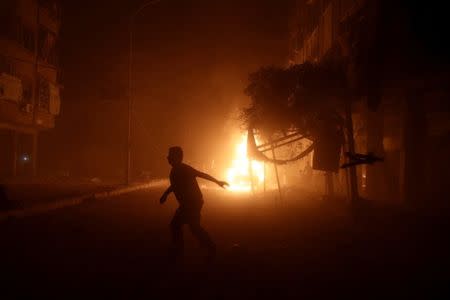 A man runs near a burning car after an airstrike in the rebel held Douma neighbourhood of Damascus, Syria October 3, 2016. REUTERS/Bassam Khabieh