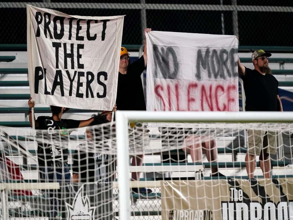 Fans hold signs in support of the players during an NWSL soccer match between the North Carolina Courage and Racing Louisville FC on Wednesday. (Gerry Broome/The Associated Press - image credit)