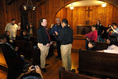 Darren Black Bear (R) reads his vows from his cellphone to Jason Pickel (L) as they are married by Darren's father Rev. Floyd Black Bear (C) in El Reno, Oklahoma October 31, 2013. REUTERS/Rick Wilking