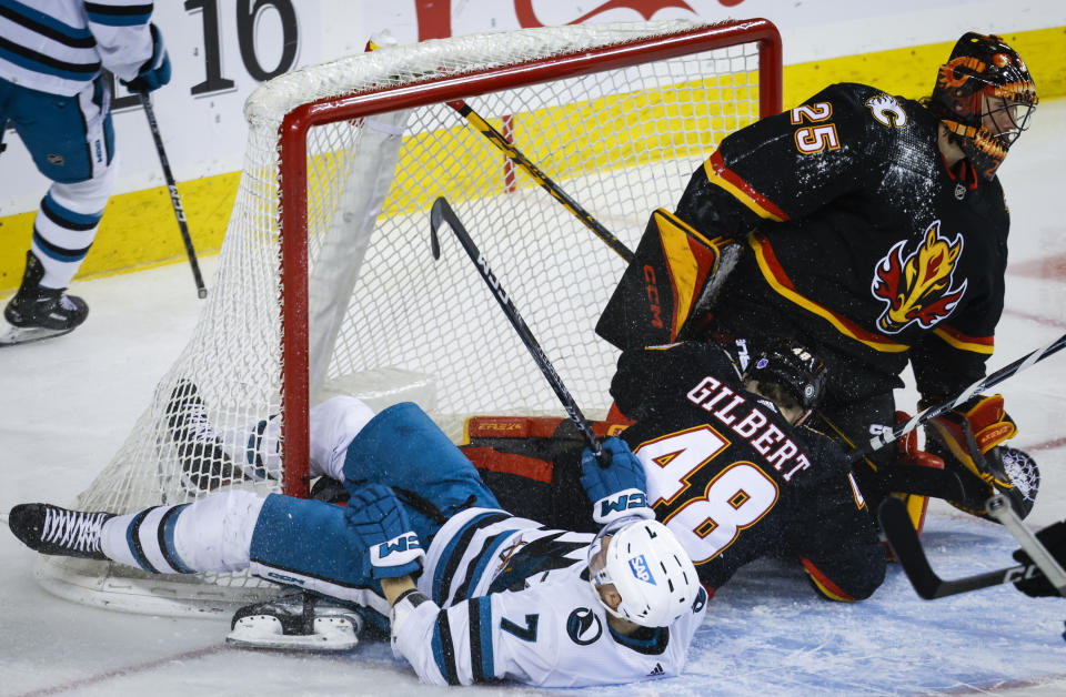 San Jose Sharks forward Nico Sturm, left, crashes into the net with Calgary Flames defenceman Dennis Gilbert, center, after scoring on goalie Jacob Markstrom during the second period of an NHL hockey game in Calgary, Alberta, Saturday, March 25, 2023.(Jeff McIntosh/The Canadian Press via AP)