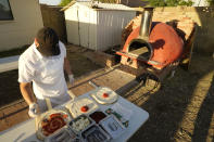 Chef Jose Hernandez preps several pizzas at a makeshift backyard pizza kitchen on April 3, 2021, in Scottsdale, Ariz. Beaten down by the pandemic, some laid-off or idle restaurant workers have pivoted to dishing out food from home. (AP Photo/Ross D. Franklin)