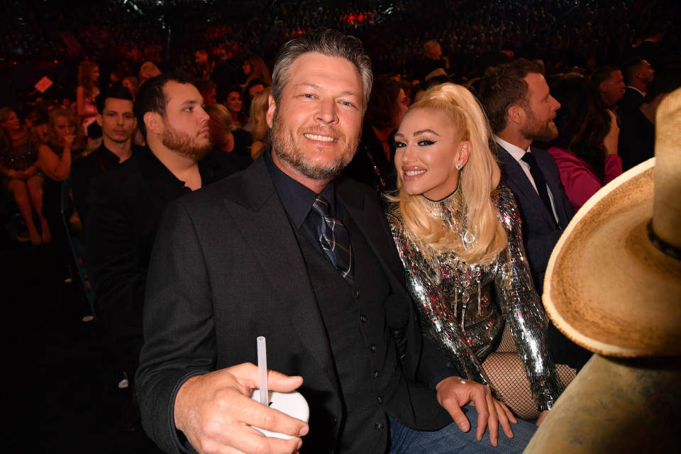 Blake Shelton in a suit and Gwen Stefani in a sparkly outfit, seated at an event