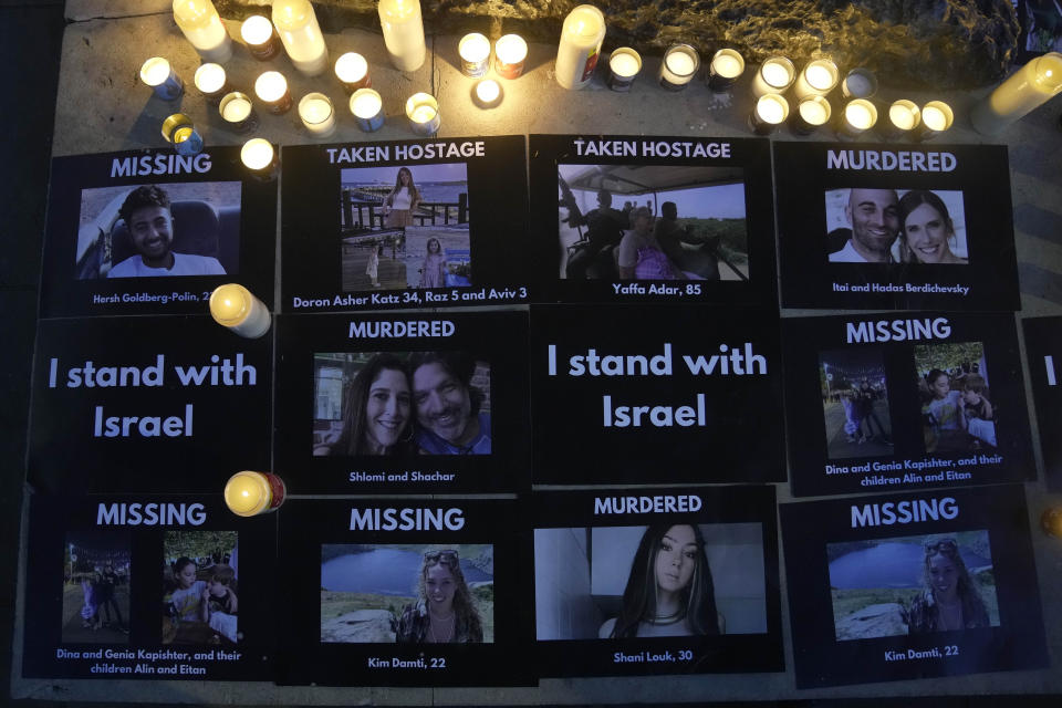 Pictures are put together on a pavement beside candles during the 'Jewish Community Vigil' for Israel in London, Monday, Oct. 9, 2023 two days after Hamas fighters launched an unprecedented, multi-front attack on Israel which killed more than 700 people. The militants blew through a fortified border fence and gunned down civilians and soldiers in Israeli communities along the Gaza frontier during a Jewish holiday. (AP Photo/Kin Cheung)