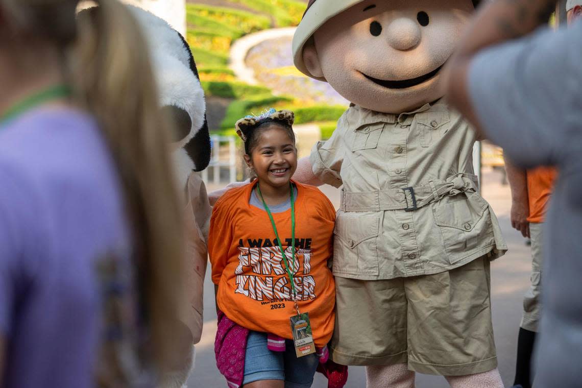 Seven-year-old Isabella Arriaza poses for a photo with characters Snoopy and Charlie Brown before riding the reimagined Zambezi Zinger rollercoaster at Worlds of Fun on Friday, June 16, 2023, in Kansas City. Emily Curiel/ecuriel@kcstar.com