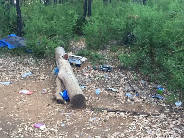 A beer box, water bottles and other pieces of rubbish can be seen surround a log at the Lake Navarino Holiday Park campground.