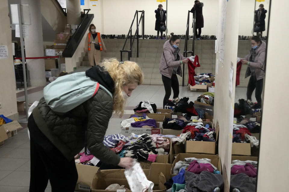Refugees from Ukraine look for clothes at a sports hall turned refugee center in Warsaw, Poland, Friday, March 18, 2022. (AP Photo/Czarek Sokolowski)