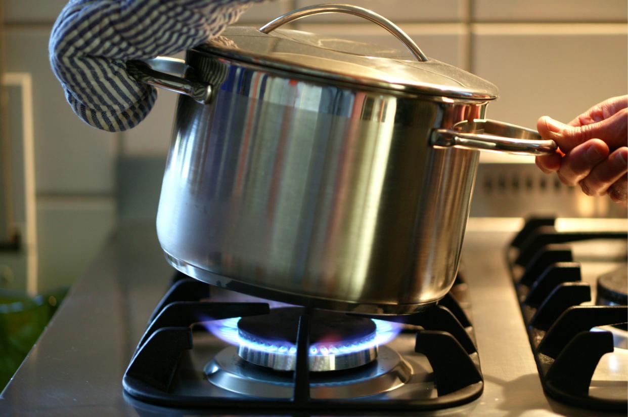 A pot is beeing taken from the gas cooker.