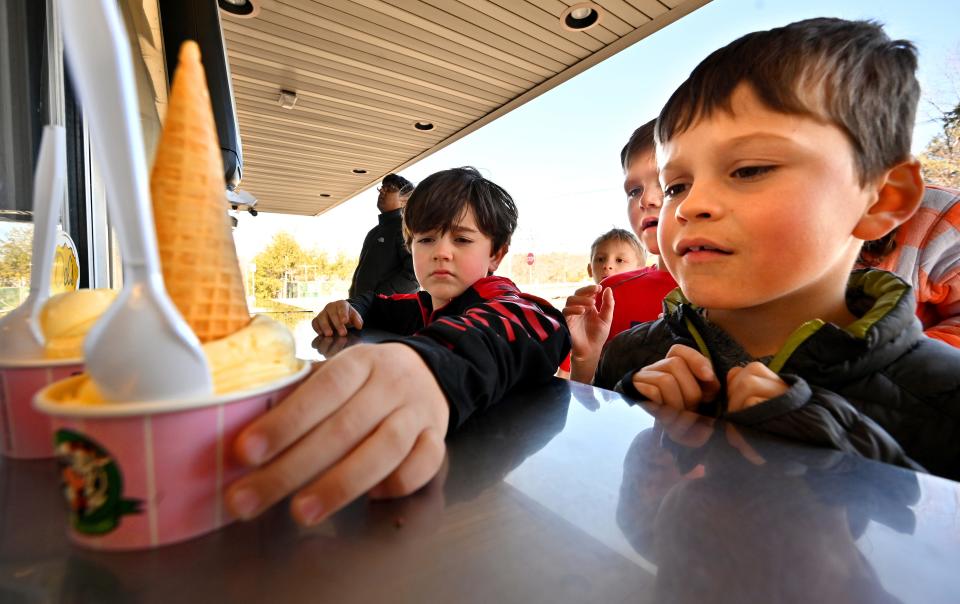 Pierce O'Donnell, 8, right, reaches for a cone in a cup as he and his friends enjoy a cool afternoon break at Uhlman's Ice Cream in Westborough, March 20, 2023. All are from Hopkinton.