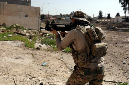 An Iraqi rapid response member aims his weapon as he secures the road for his comrades and journalists in western Mosul, Iraq March 9, 2017. REUTERS/Zohra Bensemra