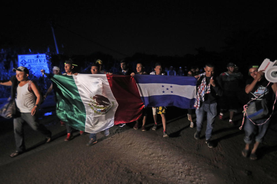 Central American migrants traveling with a caravan to the U.S. walk holding national flags from Mexico and Honduras, as they make their way to Mapastepec, Mexico, Wednesday, Oct. 24, 2018. After a day of rest to honor a fellow traveler who died on the road on Monday, the march continues through Mexico. (AP Photo/Moises Castillo)