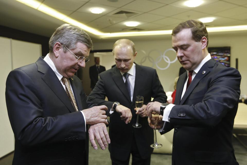 Russia's President Vladimir Putin, Prime Minister Dmitry Medvedev and International Olympic Committee (IOC) President Thomas Bach of Germany check watches before the closing ceremony for the 2014 Sochi Winter Olympics