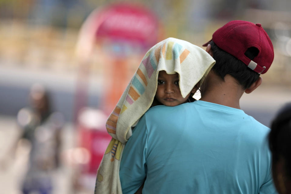 Un hombre carga a un niño, con la cabeza cubierta con una toalla para protegerlo del calor, en Jammu, India, el domingo 2 de junio de 2024. Una ola de calor extremo en la India mató a más de 100 personas el último mes. (Foto AP/Channi Anand, Archivo)