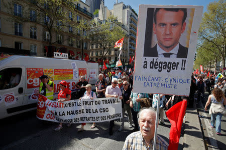 A protestor holds a placard with an image of French President Emmanuel Macron and the slogan "Clear off, lazy, cynical, radical" during a demonstration against the French government's reform plans in Paris as part of a national day of protest, France, April 19, 2018. REUTERS/Philippe Wojazer