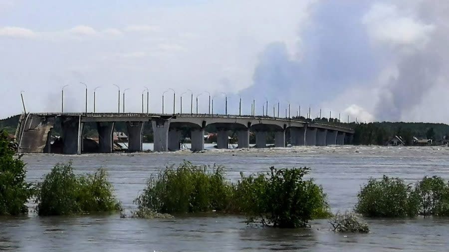 <em>This general view shows a partially flooded area near The Antonovskiy Bridge (REAR) on the outskirts of Kherson, on June 6, 2023, following damage sustained at Kakhovka hydroelectric dam. A Russian-held dam in southern Ukraine was damaged on June 6, with Kyiv and Moscow accusing each other of blowing it up while locals were forced to flee rising waters. The dam was partially destroyed by “multiple strikes”, Moscow-installed authorities claimed just as expectations were rising over the start of Ukraine’s long-awaited offensive. (Photo by Oleg TUCHYNSKY / AFP)</em>
