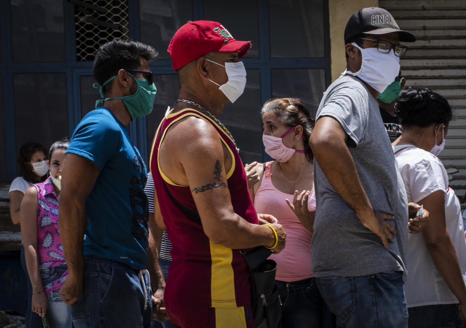 People wearing face masks amid the spread of the new coronavirus wait to enter a government-run food store in Havana, Cuba, Tuesday, May 19, 2020. State media has started a campaign of zero tolerance for anyone attempting to cash in on the fallout from the spread of the new coronavirus, like hoarding and speculative pricing, which has imposed even more distress on Cubans who were already used to shortages and long lines in their efforts to find basic necessities. (AP Photo/Ramon Espinosa)