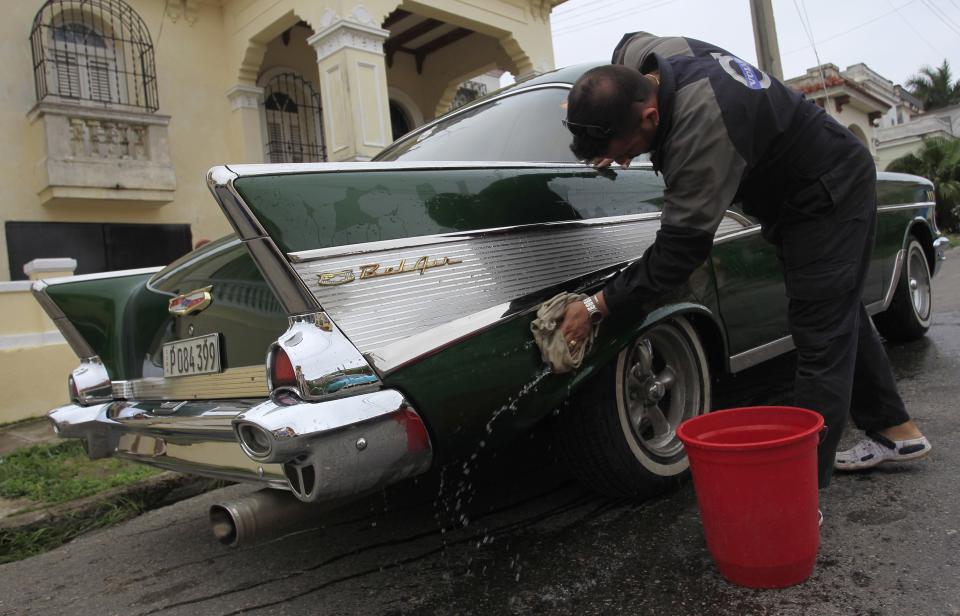 Luis Abel, 26, cleans his 1957 Chevrolet car on a street in Havana December 25, 2014. Around 60,000 vintage cars have run on Cuba's roads since before the 1959 revolution led by Fidel Castro, but finding a collectible of value is a challenge. For every hidden gem, there are thousands of beaten up clunkers, largely stripped of their original parts. Picture taken December 25, 2014. To match Feature CUBA-USA/AUTOS REUTERS/Stringer (CUBA - Tags: SOCIETY TRANSPORT BUSINESS)
