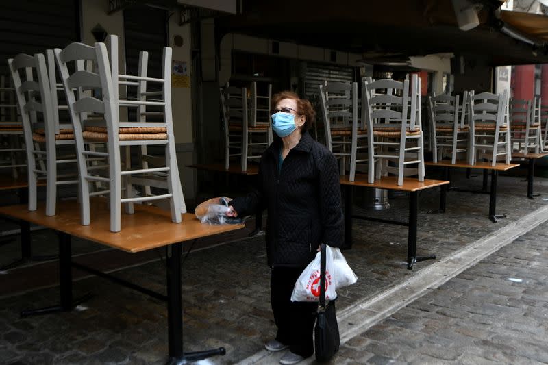 A woman stands outside a closed restaurant, amid the coronavirus disease (COVID-19) pandemic, in Thessaloniki