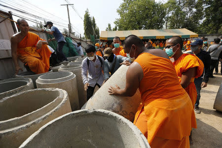 Monks set up a barricade at one of the gates of Dhammakaya temple to block soldiers who are outside the gate from accessing the temple in Pathum Thani province, Thailand February 23, 2017. REUTERS/Jorge Silva